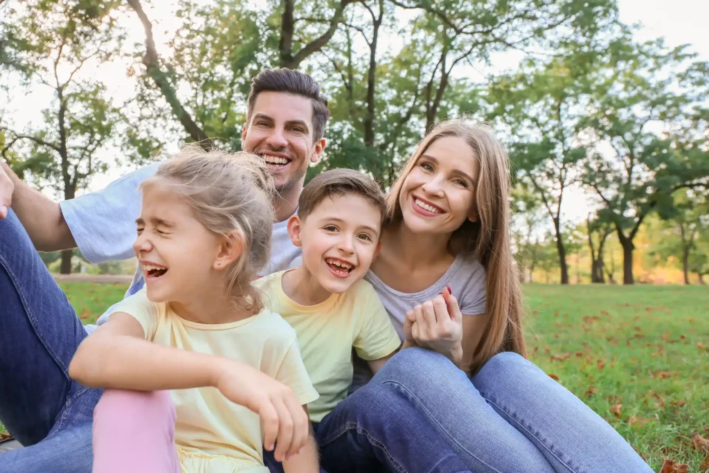 family of four sitting in the grass smiling