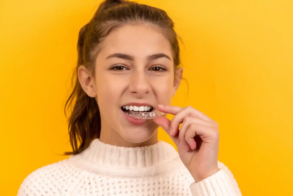 teenage girl putting in invisalign aligner