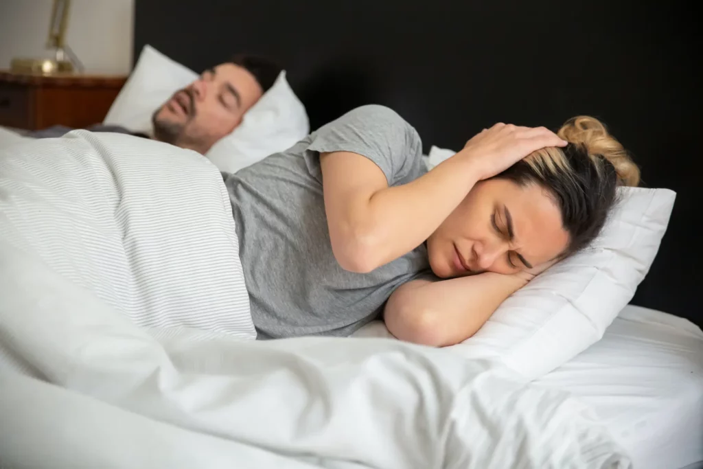 man snoring in bed with woman who is annoyed