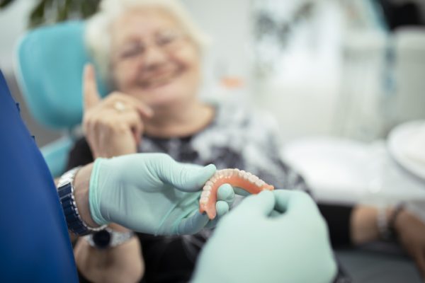 Dentist showing teeth dentures to a patient