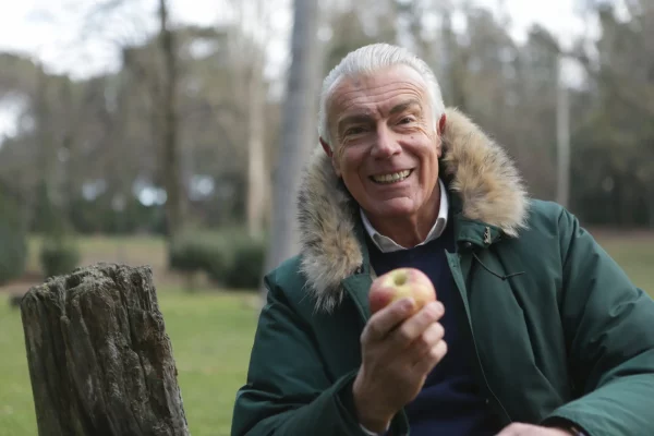 old man smiling and holding an apple